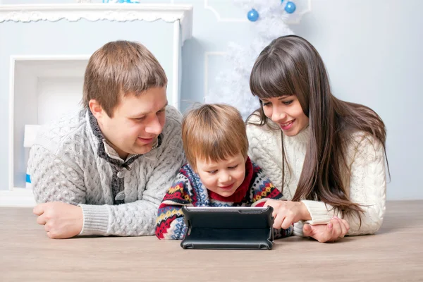 Rolig familj med tabletten nära julgran. — Stockfoto