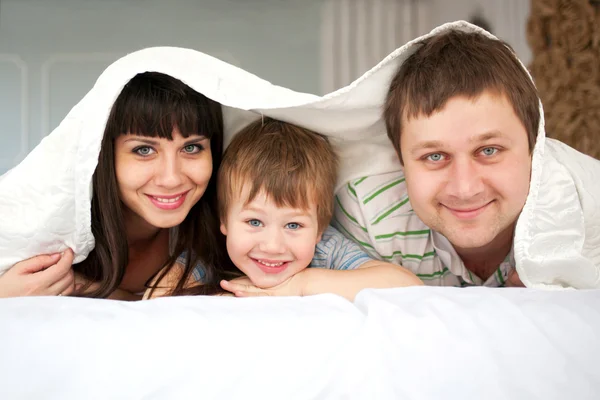 Liggend in bed en gelukkige familie — Stockfoto