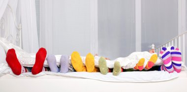 Happy family in colorful socks on white bed. clipart