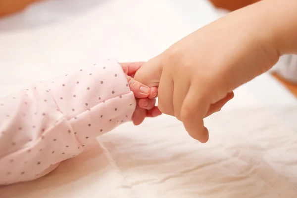 . Newborn baby holding finger of older child. — Stock Photo, Image