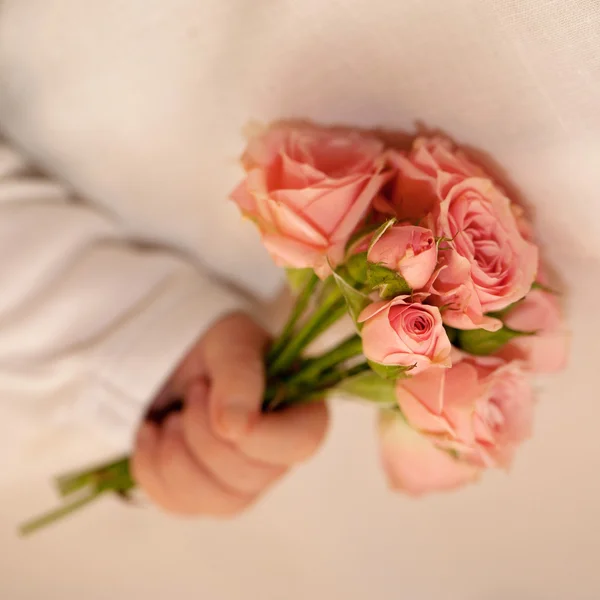 Pasgeboren baby hand met roze rozen. — Stockfoto