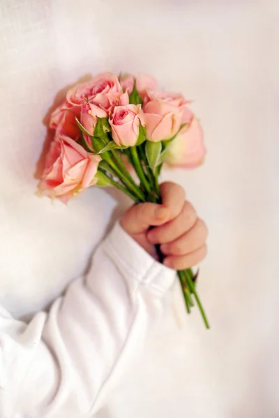 Μεγέθυνση της νεογέννητο μωρό χέρι με λουλούδια — Φωτογραφία Αρχείου