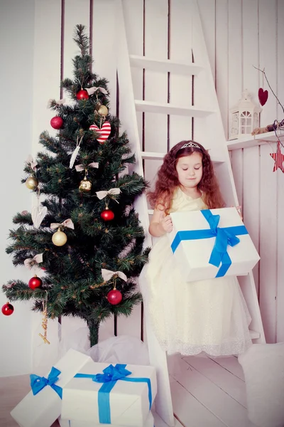 Feliz niño sonriente sosteniendo regalos cerca del árbol de Navidad . — Foto de Stock