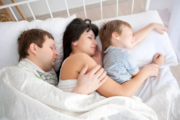 Happy family lying in bed and sleeping. — Stock Photo, Image