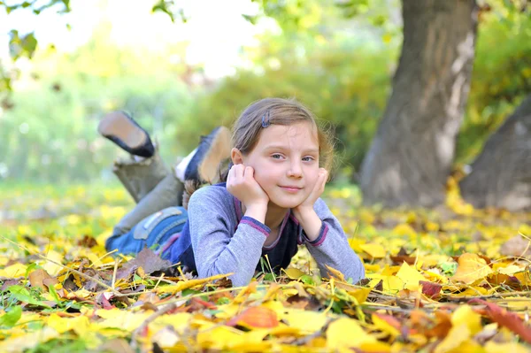 Kleines Mädchen legt sich auf die Blätter — Stockfoto