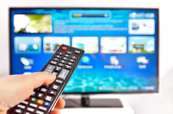 Smart tv and hand pressing remote control — Stock Photo, Image