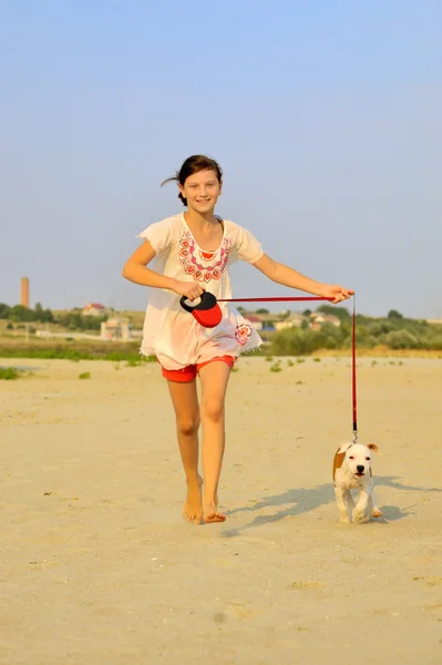 Girl playing with her dog on the sand — Stock Photo, Image