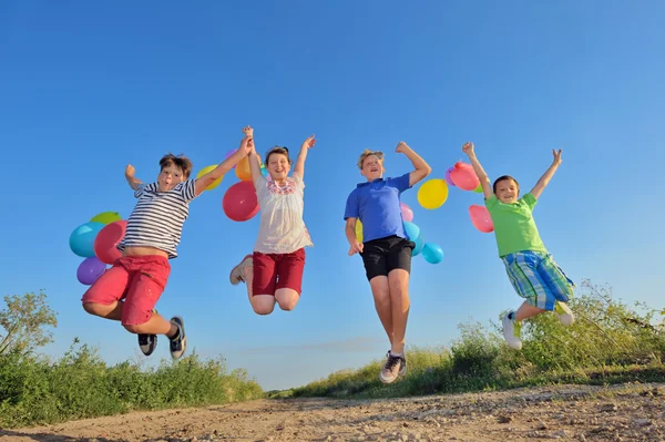 Niños felices saltando en el campo con globos — Foto de Stock