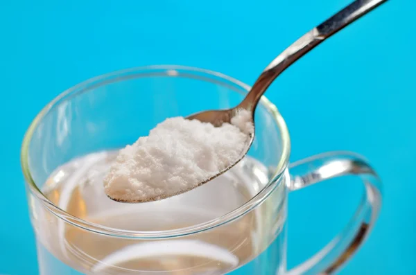 Cuchara de bicarbonato de sodio sobre un vaso de agua — Foto de Stock