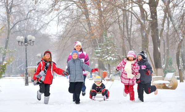 Groupe d'enfants et mère jouant sur la neige en hiver — Photo