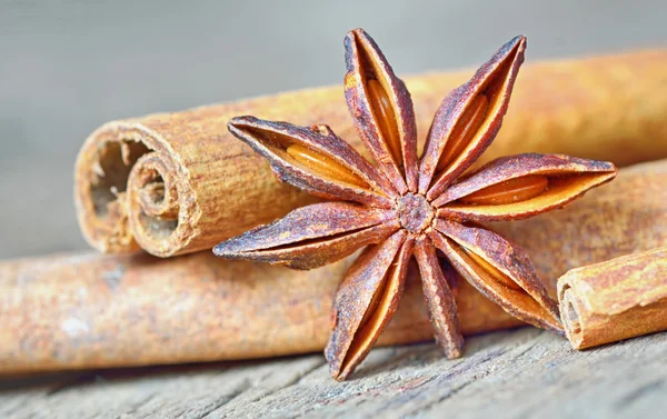 Ahşap masa üzerinde anason yıldızlı ve tarçın çubukları — Stok fotoğraf