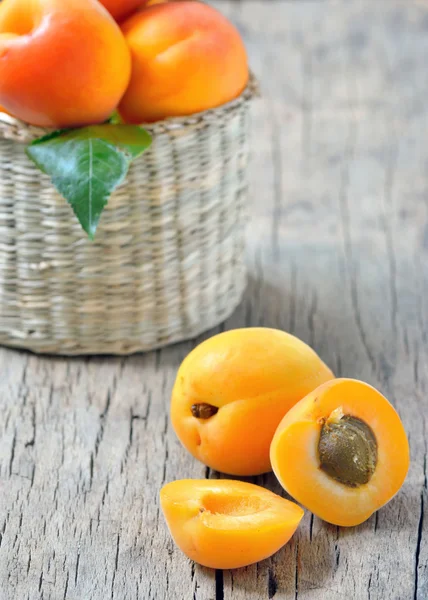 Apricots on the old wooden table and basket shoot in studio — Stock Photo, Image