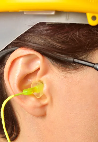 Yellow earplug into the ear — Stock Photo, Image