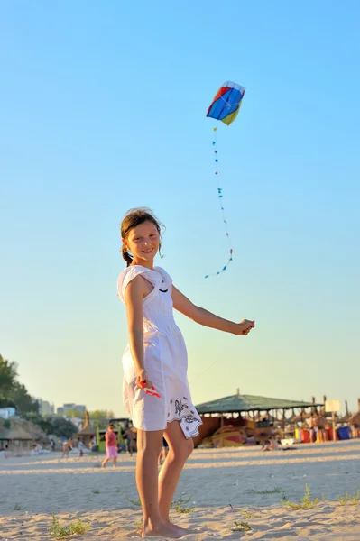 Jovem menina voando um papagaio na praia — Fotografia de Stock