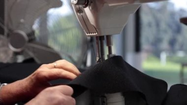 Eller sanayi makinesiyle siyah kumaş dikiyor. Kumaş elementleri ve kumaşlar için otomatik makineyle endüstriyel dikiş.