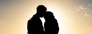 Güzel günbatımında ayakta duran klasik sırt çantası takan genç hippi çiftlerin silueti ile yatay pankart - aşk kavramı ve gençlik kültürü