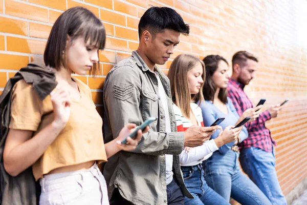 在大学后院里使用智能手机的多文化人群 对手机上瘾的千年朋友 总是连接学生的技术概念 温暖生动的过滤器 — 图库照片
