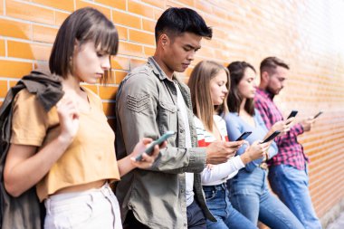 Üniversitenin arka bahçesinde akıllı telefon kullanan çok kültürlü insanlar grubu cep telefonu bağımlısı Milenyal arkadaşlar her zaman bağlı öğrencilere sahip teknoloji konsepti