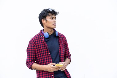 İzole edilmiş genç Asyalı adam beyaz arka planda cep telefonu kullanıyor. Z nesli ve milenyum insanları her zaman birbirlerine bağlıdır.