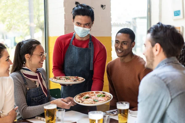 在舒适的比萨饼店餐厅为朋友们提供美味的比萨饼 多民族朋友在比萨饼店一起吃比萨饼和喝金发啤酒 — 图库照片