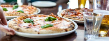 Yatay pankart ya da başlık Margherita Napoli usulü bufalo mozzarella, domates sosu ve fesleğenli pizza servisi yapan yakın plan pizza.
