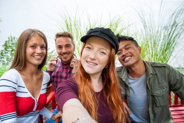 Çok kültürlü erkekler ve kızlar dışarıda selfie çekiyorlar. Çok ırklı gençler üzerinde mutlu bir arkadaşlık konsepti. Birlikte eğleniyorlar.