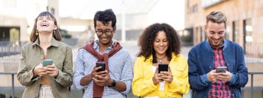 Horizontal banner or header with multiracial friends laughing using smartphone in the university district of the city - Young people addicted by mobile smart phones