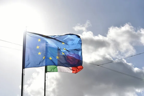 European flag and italian flag waving together in a clear blue sky. Relationship between the European Union and the Italy. Concepts.