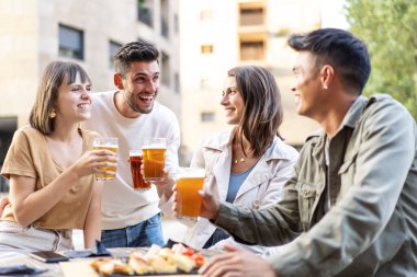 Bira fabrikasının bahçesinde bira içen çok ırklı arkadaşlar erkek ve kızlarla birlikte açık hava bar iğrençliğinde mutlu saat yemeklerinin tadını çıkaran hakiki arkadaşlık tarzı konsept.
