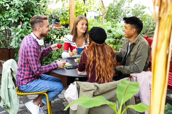 年轻人在咖啡馆酒吧花园喝浓缩咖啡和美国咖啡 快乐的朋友们在旅舍里聊天和玩乐 快乐的男人和女孩在露天咖啡馆里的生活方式概念 — 图库照片