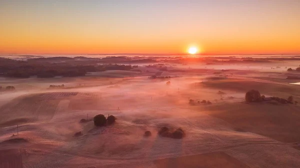 Amazing Sunrise Light Above Misty Landscape. Scenic View Of Foggy Morning In Misty fields in Lithuania