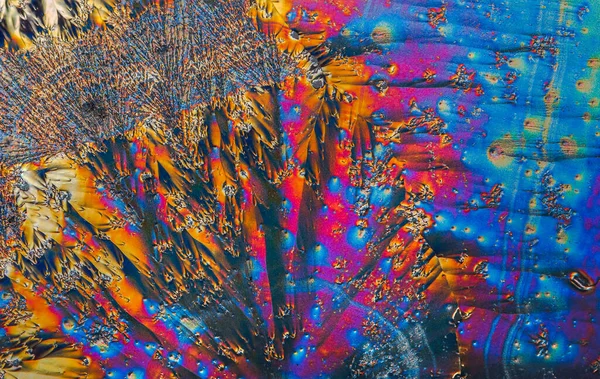 Ekstremalne makro zdjęcie kryształów witaminy C tworzących abstrakcyjne wzory sztuki nowoczesnej, oświetlone światłem polaryzacyjnym, pod mikroskopem obiektywu o 10-krotnym powiększeniu — Zdjęcie stockowe