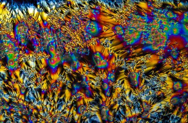 C vitamini kristallerinin uç makro fotoğrafları, polarize ışıkla aydınlatıldığında, 10x büyütme ile mikroskop altında soyut modern sanat modelleri oluşturur.