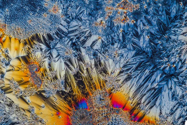 Extreme Makroaufnahme von Vitamin-C-Kristallen, die abstrakte Muster moderner Kunst bilden, wenn sie mit polarisiertem Licht unter einem Mikroskopobjektiv mit 10-facher Vergrößerung beleuchtet werden — Stockfoto