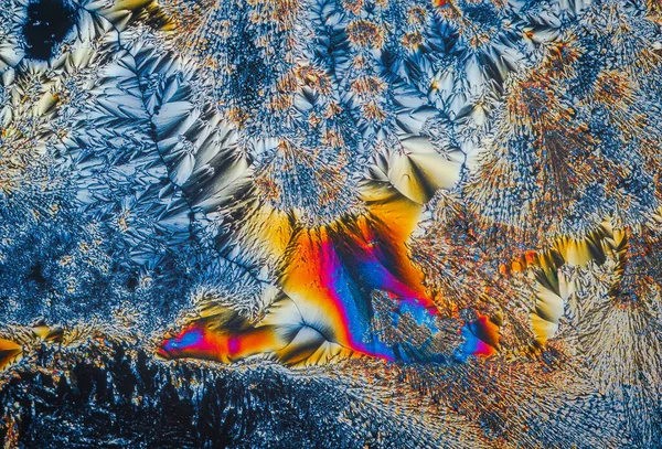 Extreme macro photograph of Vitamin C crystals forming abstract modern art patterns, when illuminated with polarized light, under a microscope objective with 10x magnification — 스톡 사진