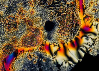 C vitamini kristallerinin uç makro fotoğrafları, polarize ışıkla aydınlatıldığında, 10x büyütme ile mikroskop altında soyut modern sanat modelleri oluşturur.