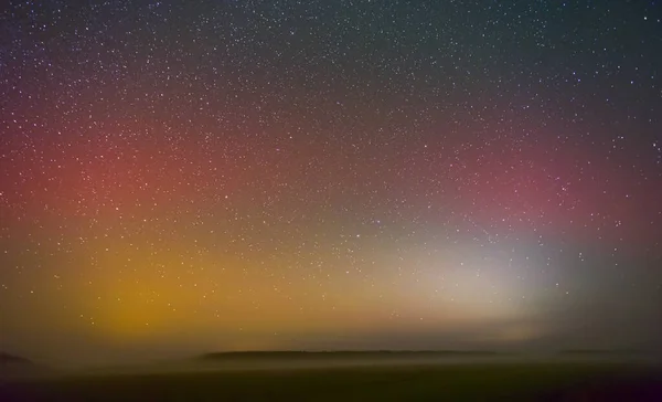 Brilho vermelho das luzes do Norte - Aurora boreal sobre os campos na Lituânia — Fotografia de Stock