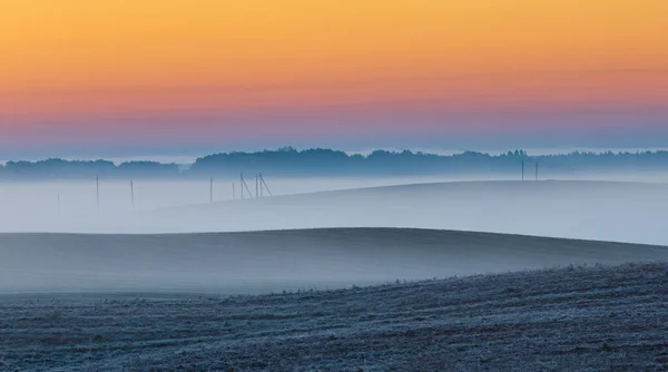 Kék ködhullámok napkelte előtt a rétek között, hideg kora téli reggel. — Stock Fotó