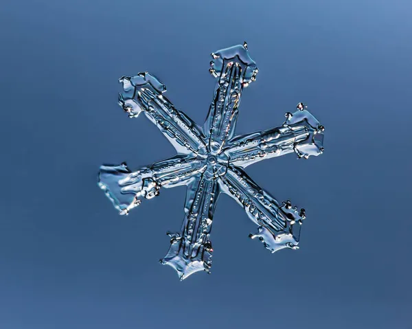 Vločka na hladkém gradientu pozadí. Makro fotografie skutečného sněhového krystalu na skleněném povrchu. To je malá sněhová vločka s neobvyklým vzorem. — Stock fotografie