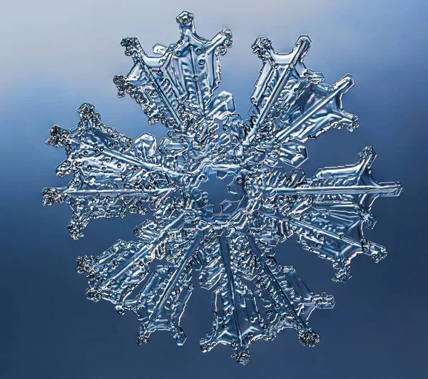 Snowflake on smooth gradient background. Macro photo of real snow crystal on glass surface. This is small snowflake with unusual pattern. — Stock Photo, Image