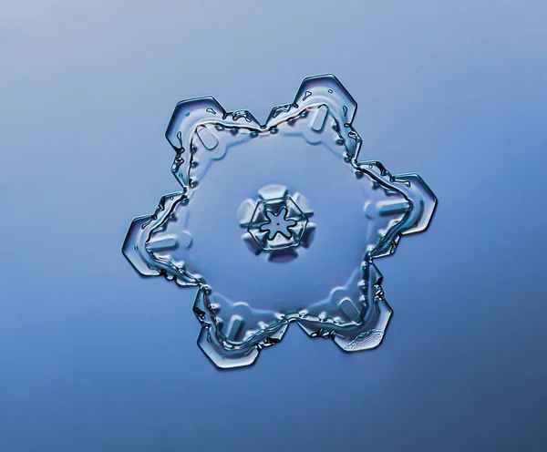 Сніжинка на гладкому градієнтному фоні. Макро фото реального снігового кристалу на скляній поверхні. Це невеликий сніжинка з незвичайним візерунком . — стокове фото