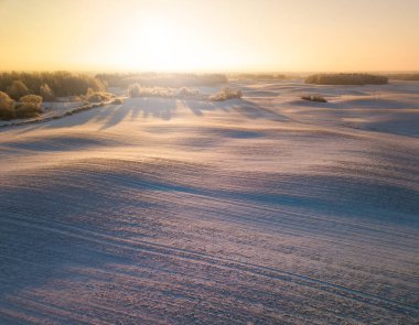 Winter aerial panorama with wavy meadows covered in snow, early morning light, early spring