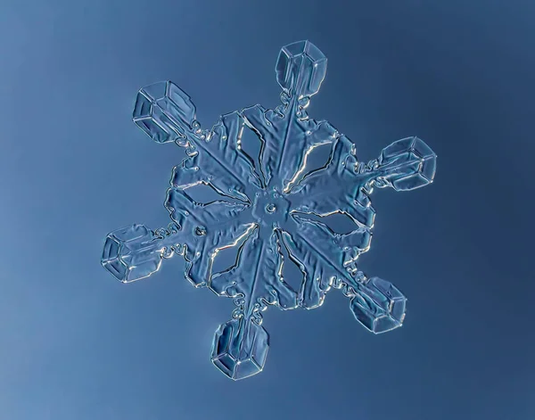 Vločka na hladkém gradientu pozadí. Makro fotografie skutečného sněhového krystalu na skleněném povrchu. To je malá sněhová vločka s neobvyklým vzorem. — Stock fotografie