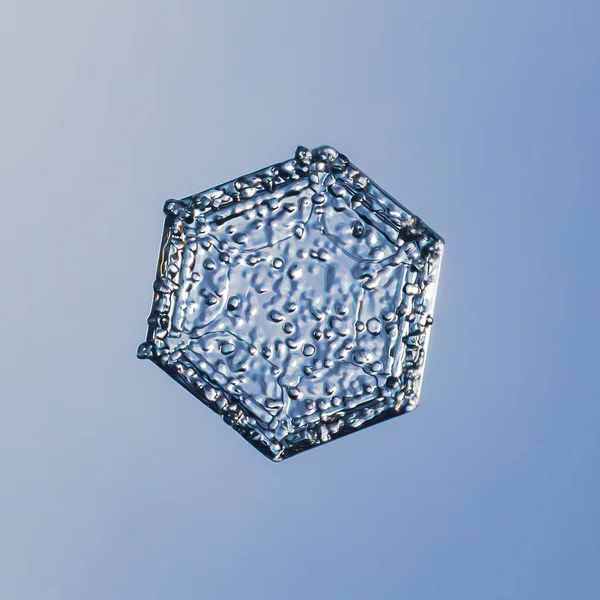 Sneeuwvlok op een gladde achtergrond. Macro foto van echt sneeuwkristal op glasoppervlak. Dit is een kleine sneeuwvlok met ongewoon patroon.. — Stockfoto