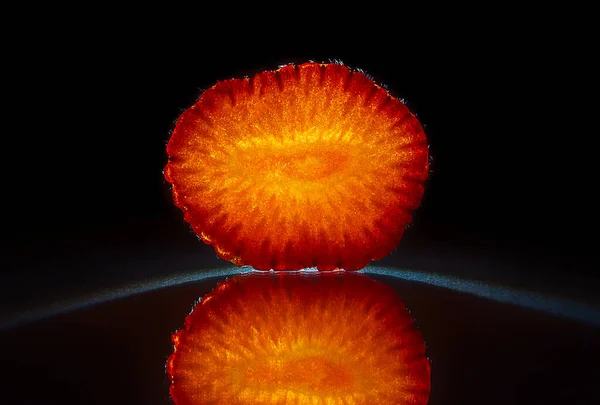 Scheibe einer Erdbeere isoliert in dunkelschwarzem Hintergrund mit Reflexion — Stockfoto