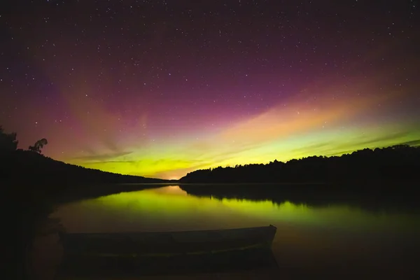 Estética do céu noturno, estrelas do céu noturno com Aurora boreal no fundo, bela vista noturna em uma viagem de estrada, barco flutuando na água — Fotografia de Stock