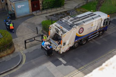 London, UK-17.04.22: a man unloading rubbish container into a rear loader truck in a City of Westminster, central London