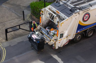 London, UK-17.04.22: a man unloading rubbish container into a rear loader truck in a City of Westminster, central London