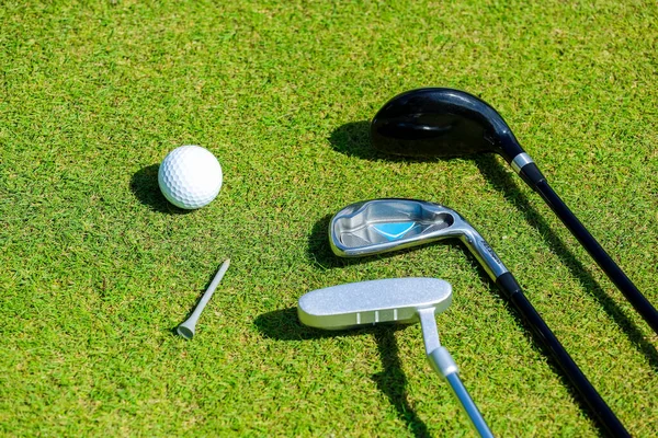 Golfklubbor och boll ligger på grönt gräs i strålar av den eviga solen — Stockfoto