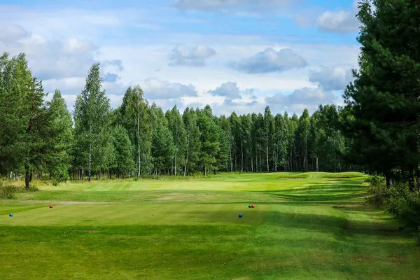 Golfové hřiště, krajina, zelená tráva na pozadí lesa a jasná obloha s mraky — Stock fotografie